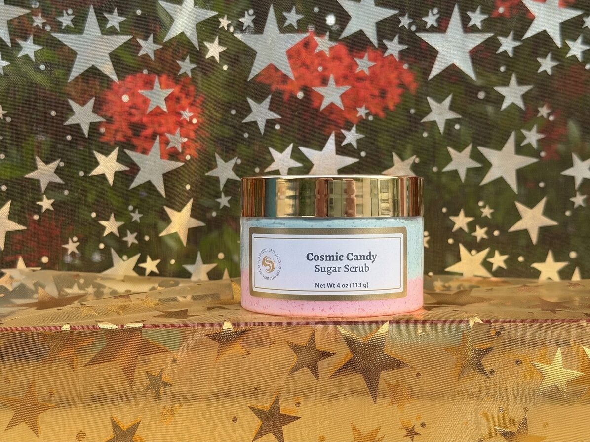 Cosmic Candy sugar scrub jar with teal and pink layers against a star-print fabric