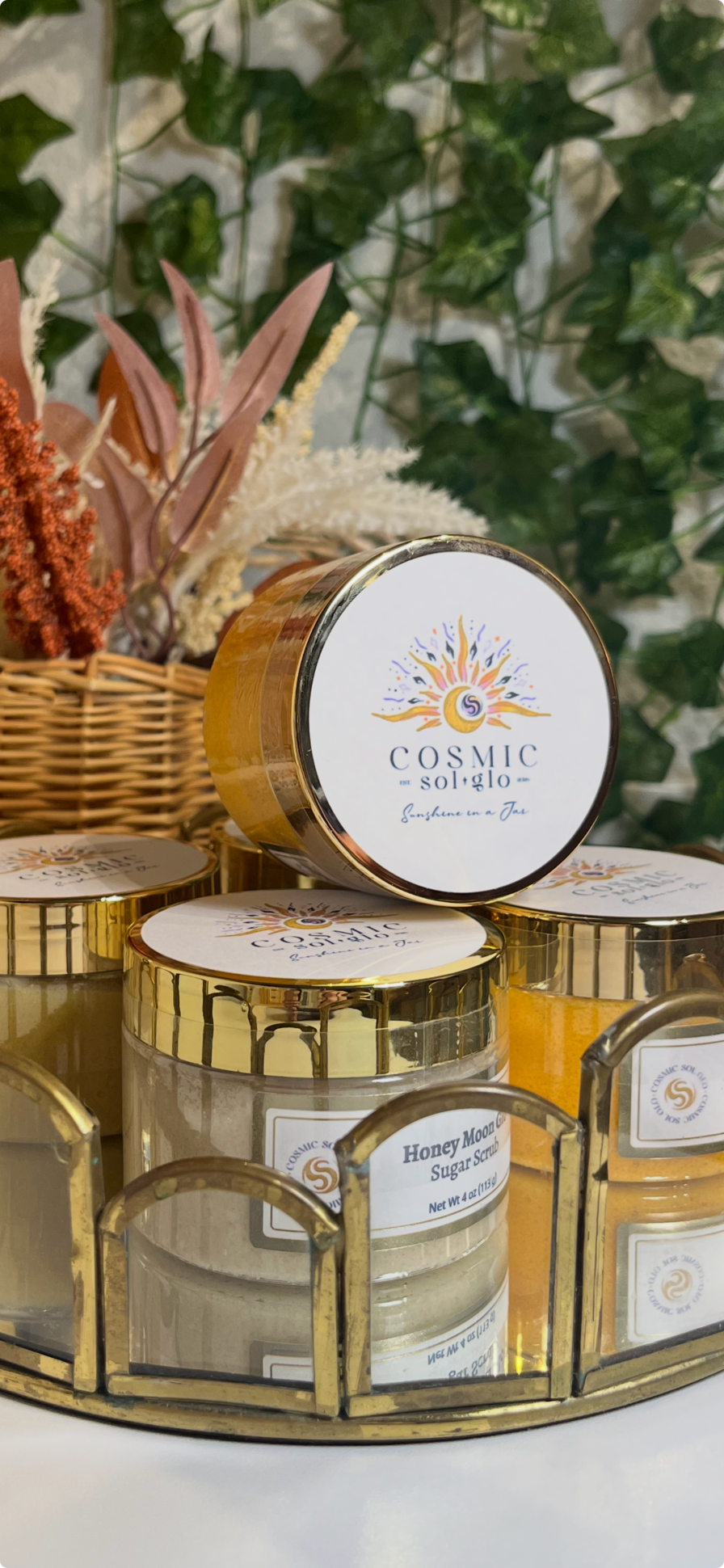 Cosmic Sol Glo jars arranged in a gold scalloped tray with trailing greenery